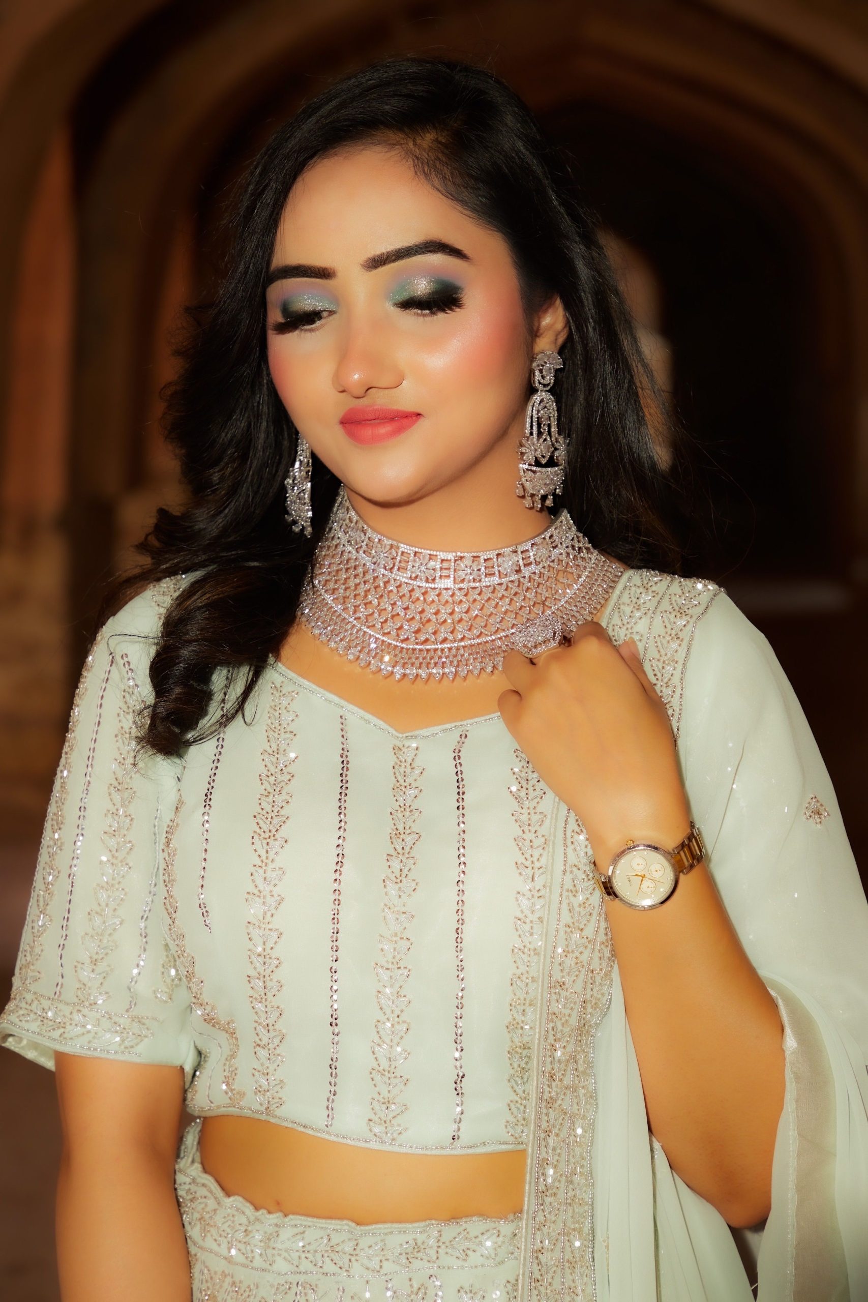 Portrait of a woman in traditional attire adorned with elegant jewelry, posing gracefully indoors.