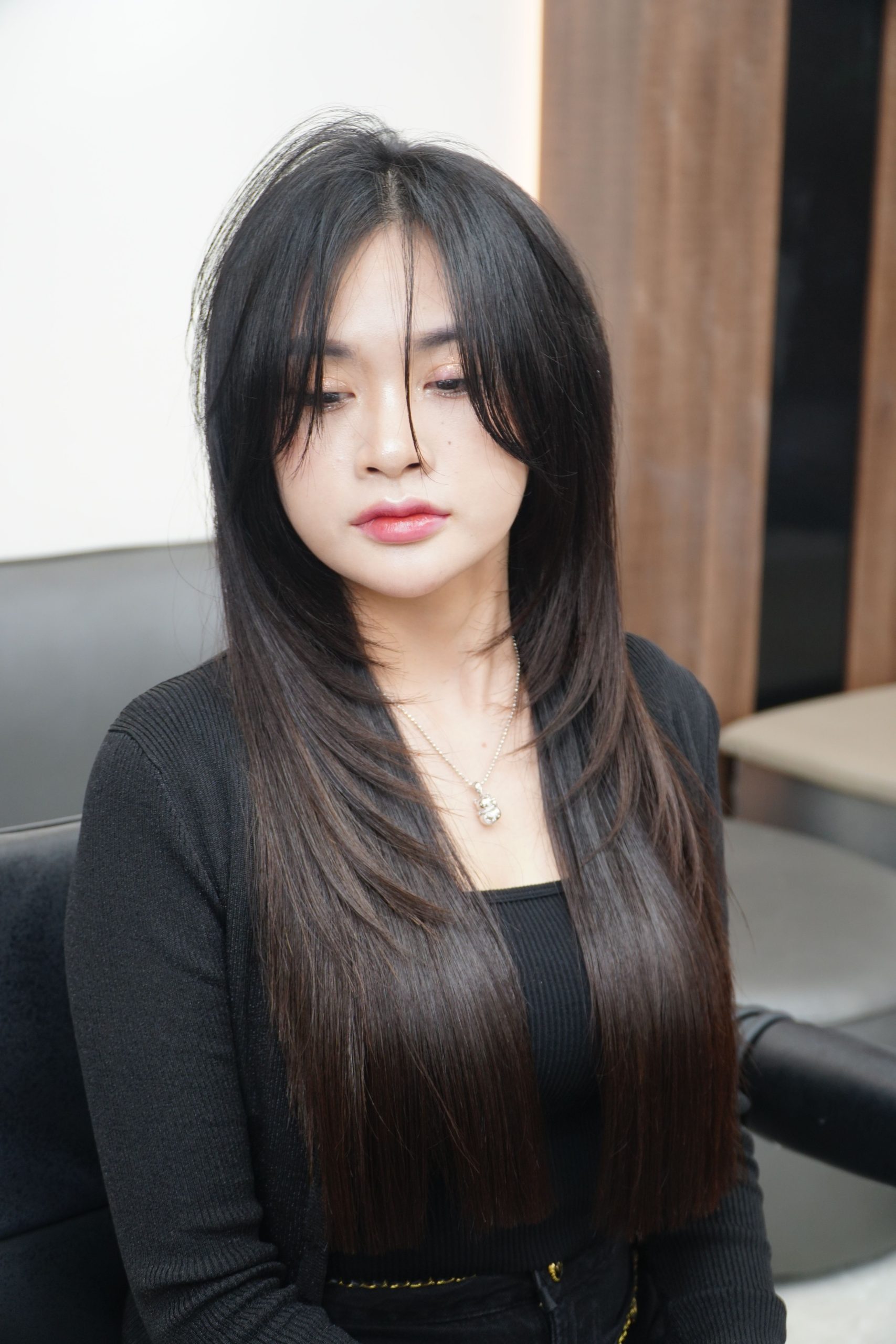 Portrait of a young woman with long straight hair sitting in a salon chair.