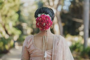 A woman in traditional attire with an elaborate floral hairstyle, captured outdoors.